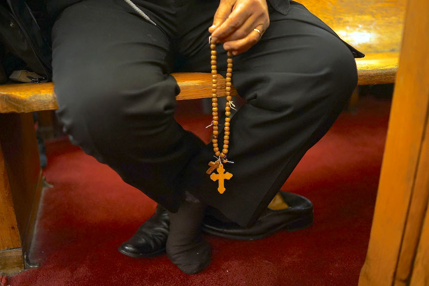 Man holds Coptic Christian cross at the Coptic Orthodox Church of St. George in Brooklyn.