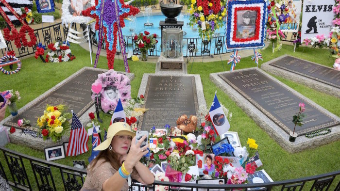 A fan takes a selfie at Elvis' grave at Graceland. Credit: Getty