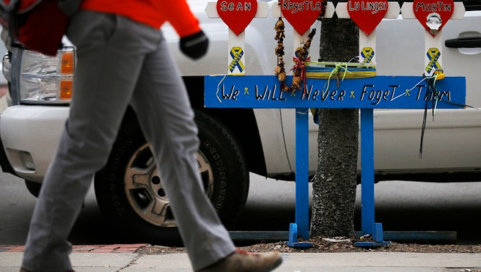 A pedestrian walks past a memorial for the victims of the Boston Marathon bombings and its aftermath near the race's finish line, on the second day of jury selection in the trial of accused Boston Marathon bomber Dzhokhar Tsarnaev in Boston, Massachusetts