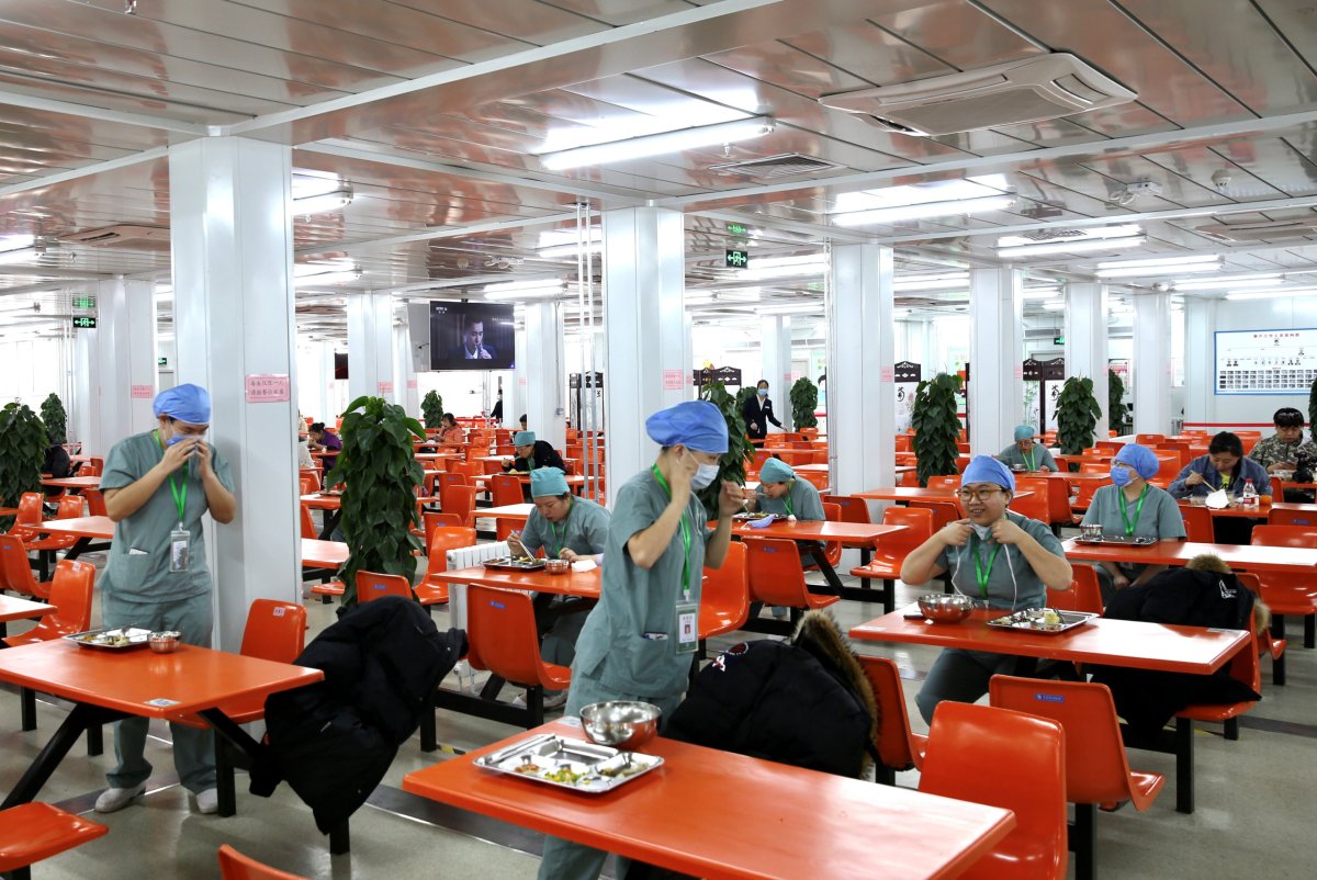 Medical workers eat at separate tables at a canteen inside