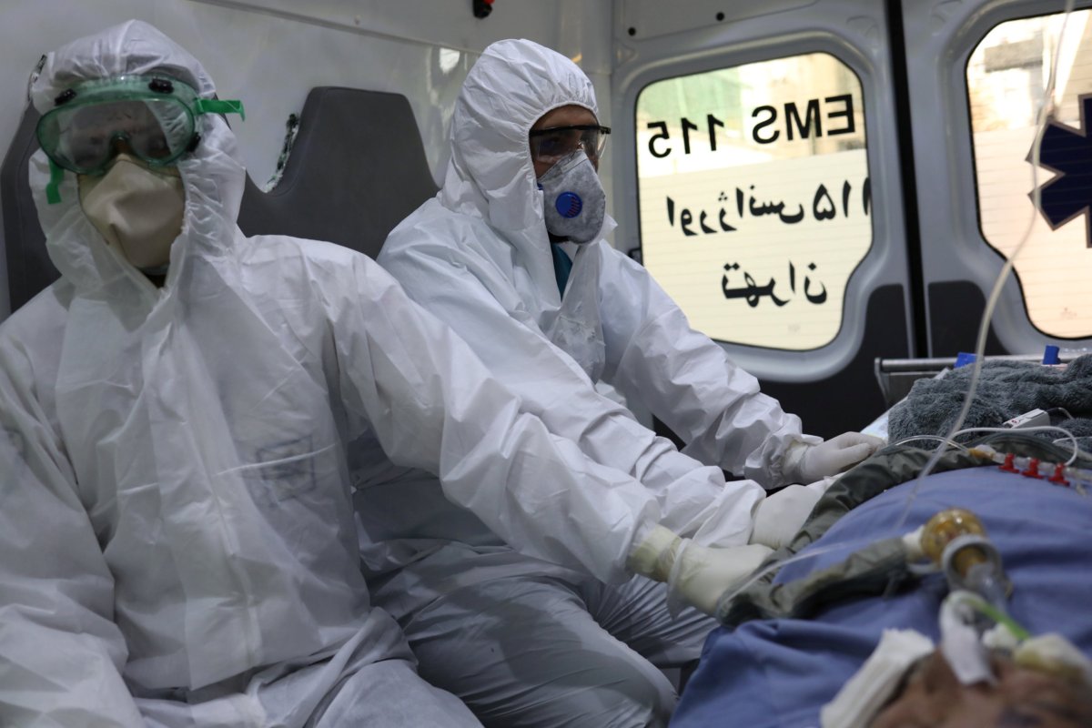 Emergency medical staff wearing protective suits, sit in an ambulance