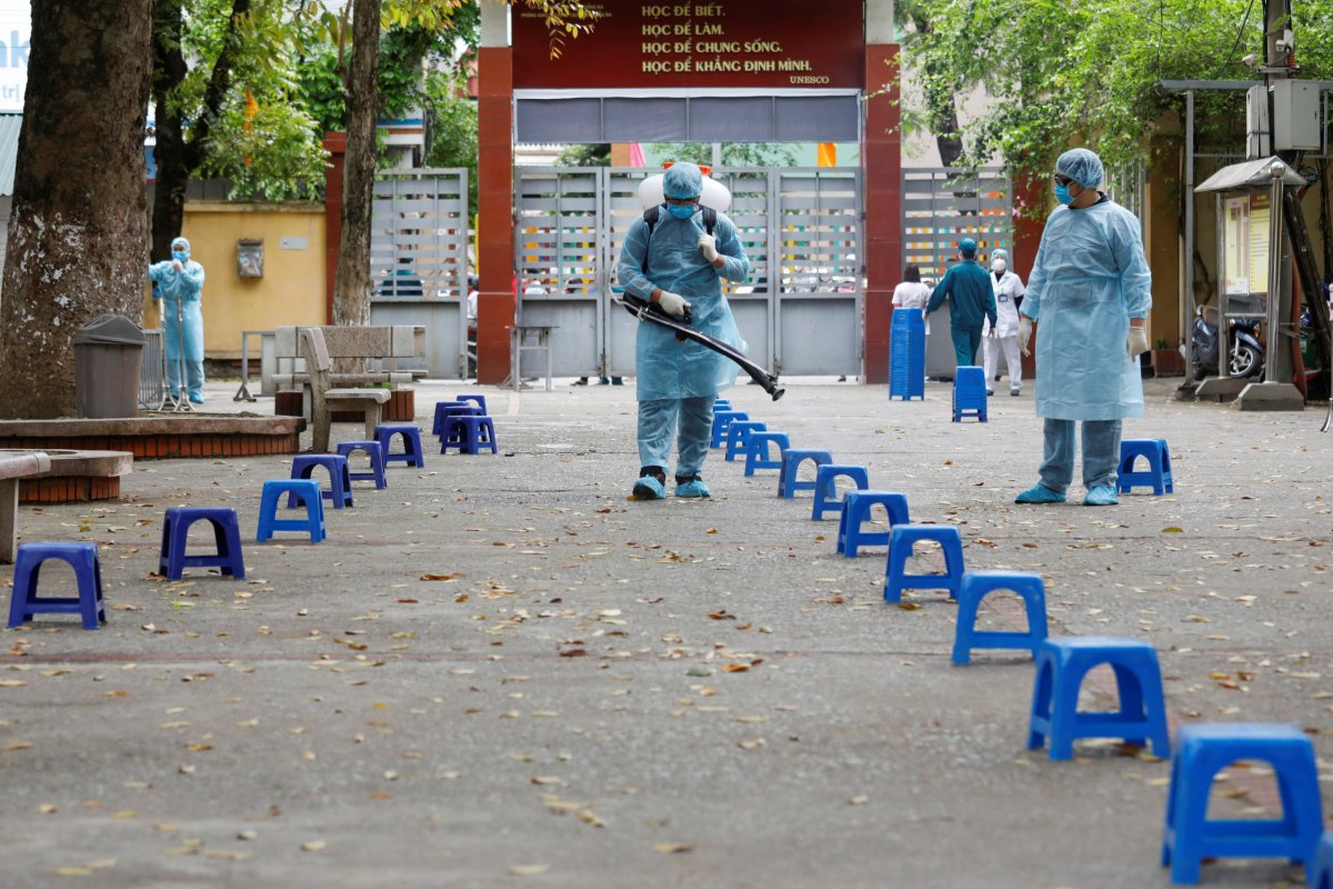Health workers wearing protective suits spray disinfectant as a preventive