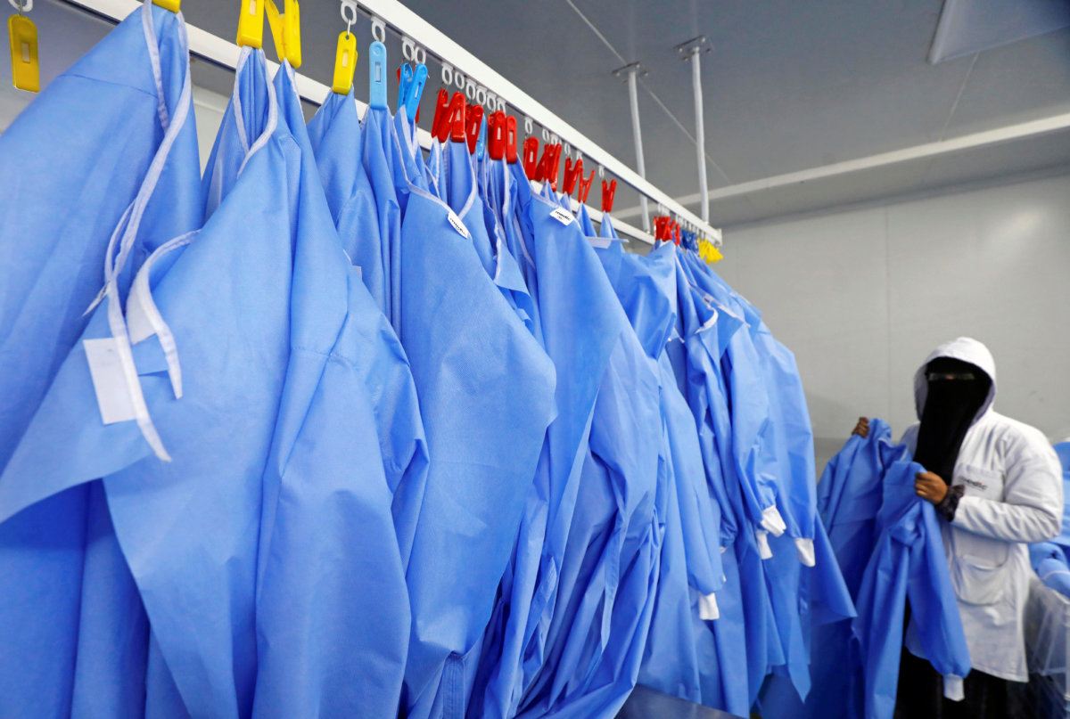 A woman hangs coats in a factory that produces sterilised