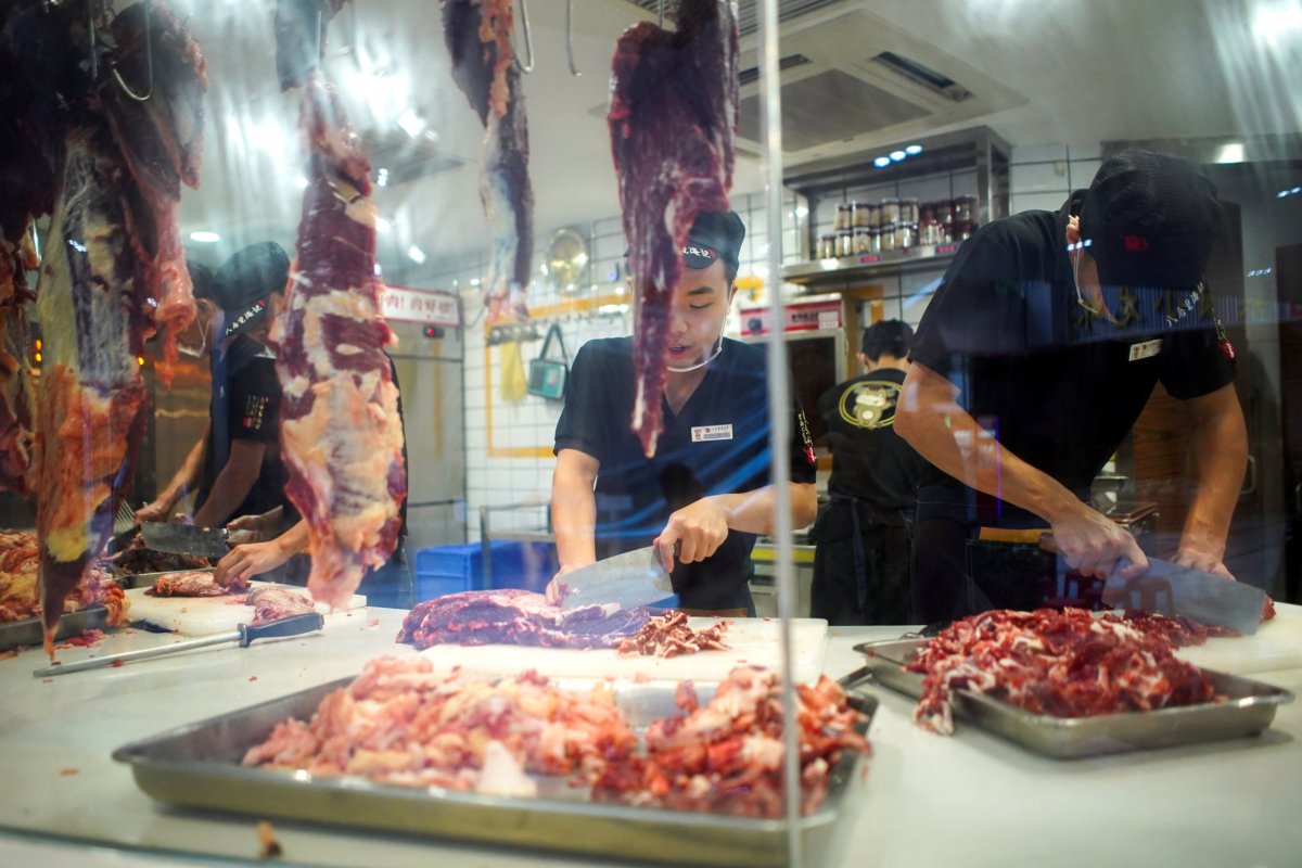 FILE PHOTO: Workers cut beef at a restaurant in Shenzhen