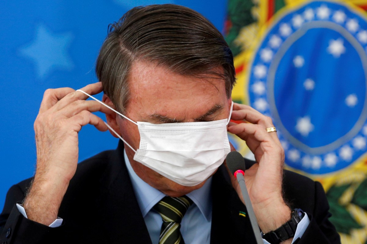 FILE PHOTO: Brazil’s Jair Bolsonaro adjusts his protective face mask