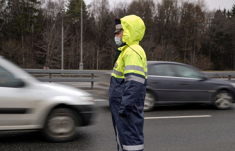 A traffic police officer wearing a protective mask observes cars