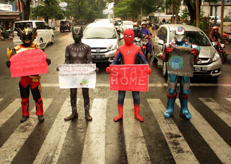 Volunteers wearing superhero costumes carry banners for a campaign against