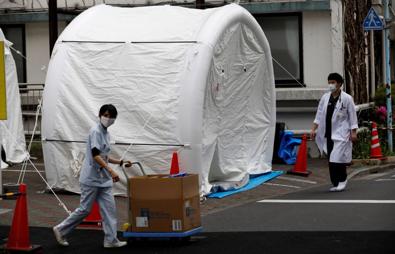 Medical workers walk by tents set up to test for