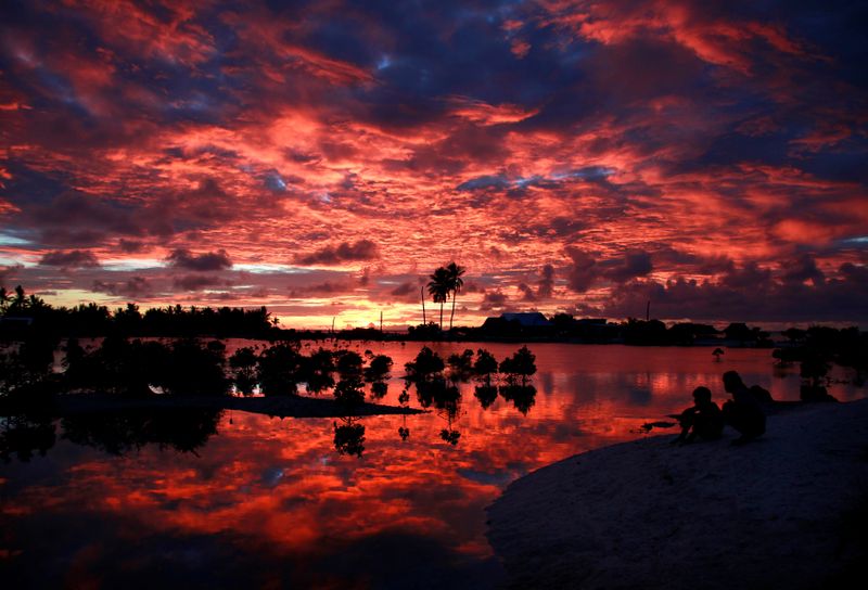 Villagers watch the sunset over a small lagoon near the
