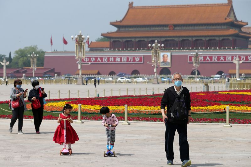 People walk past flower installations at Tiananmen Square in Beijing