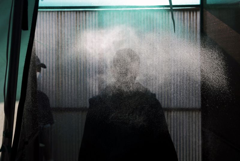 A Syrian man is sprayed with disinfectant at the entrance