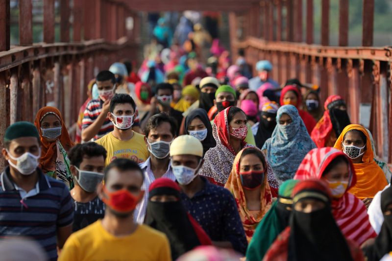 FILE PHOTO: Garment workers return from a workplace as factories