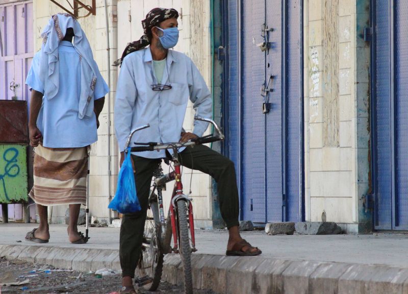 A man wearing a protecitve face mask rides a bicycle