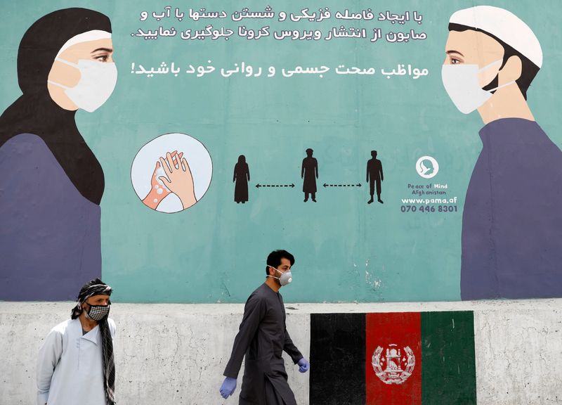 An Afghan man wearing a protective face mask walks past