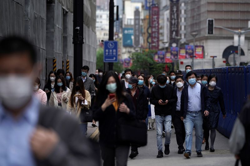 People wearing face masks walk at a main shopping area,
