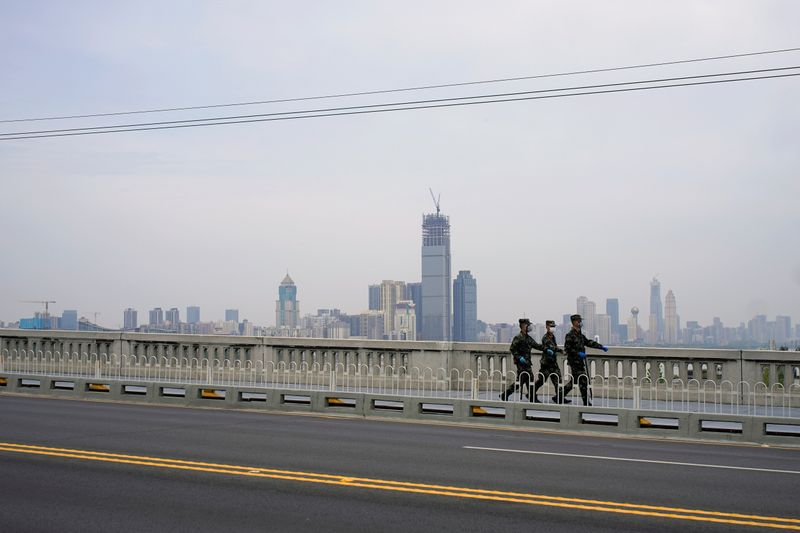 Paramilitary officers wearing face masks walk on a bridge in
