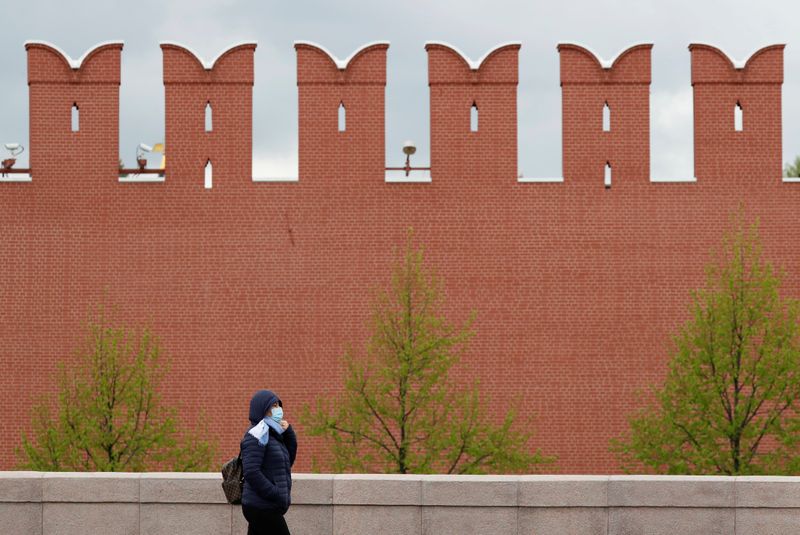 A woman walks past the Kremlin wall in Moscow