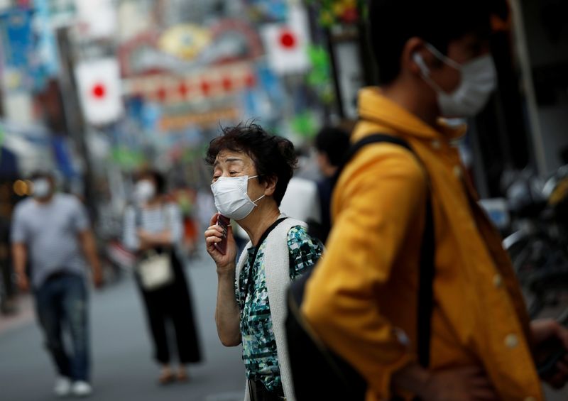 People wearing protective face masks walk on the street under