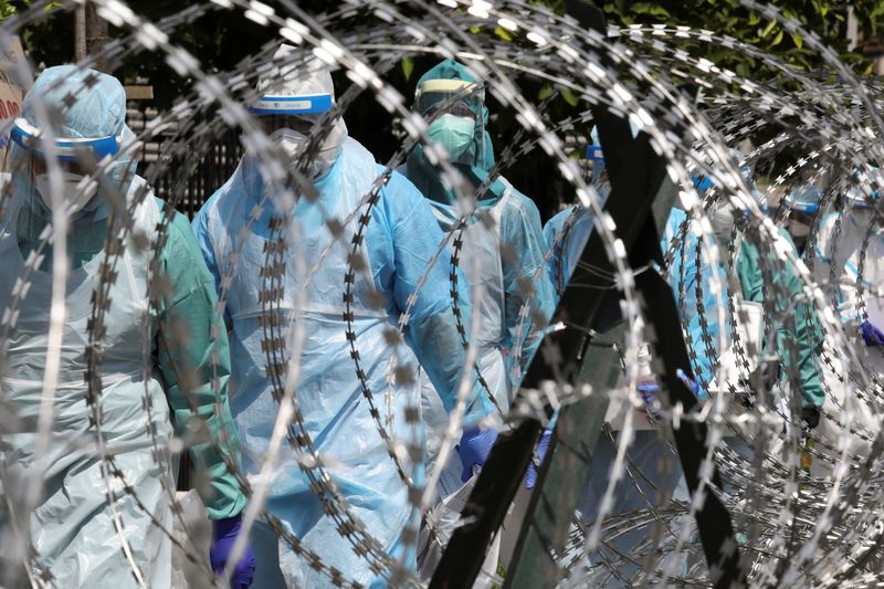 Medical workers wearing protective suits pass by barbed wire at