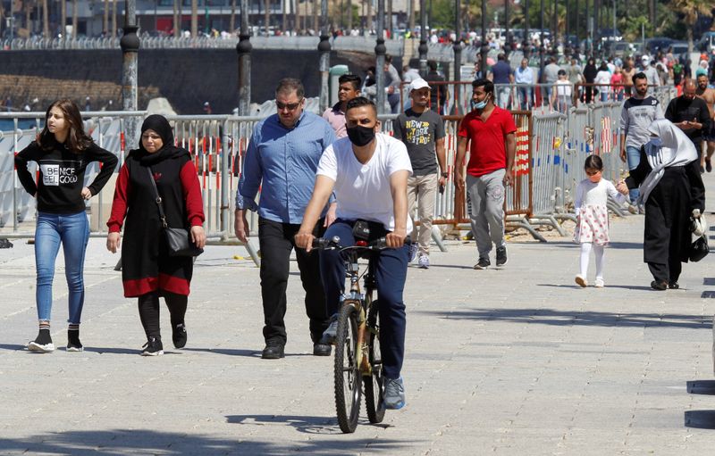 People walk and a man rides a bicycle along Beirut’s