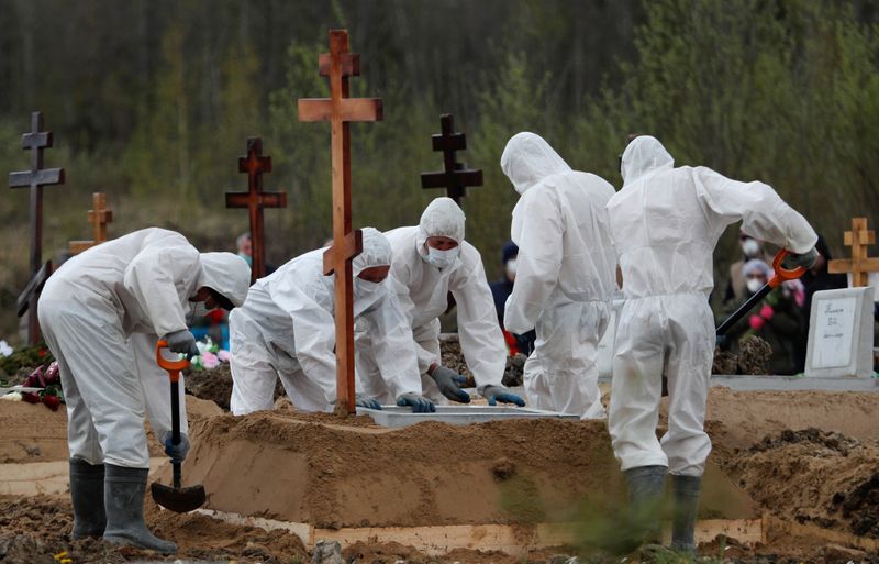 Grave diggers bury a coronavirus disease victim in Saint Petersburg