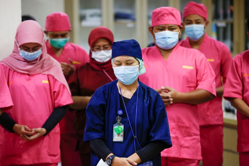 Healthcare workers wearing protective face masks pray for the coronavirus