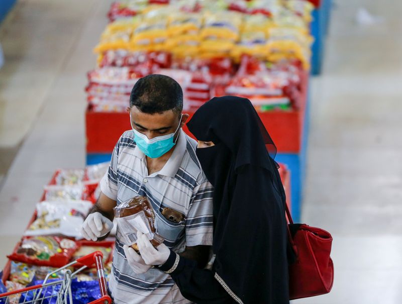 FILE PHOTO: Couple wearing protective face masks and gloves shop