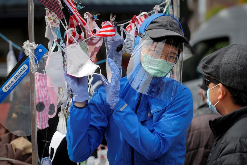 A man speaks to a street vendor about face masks,