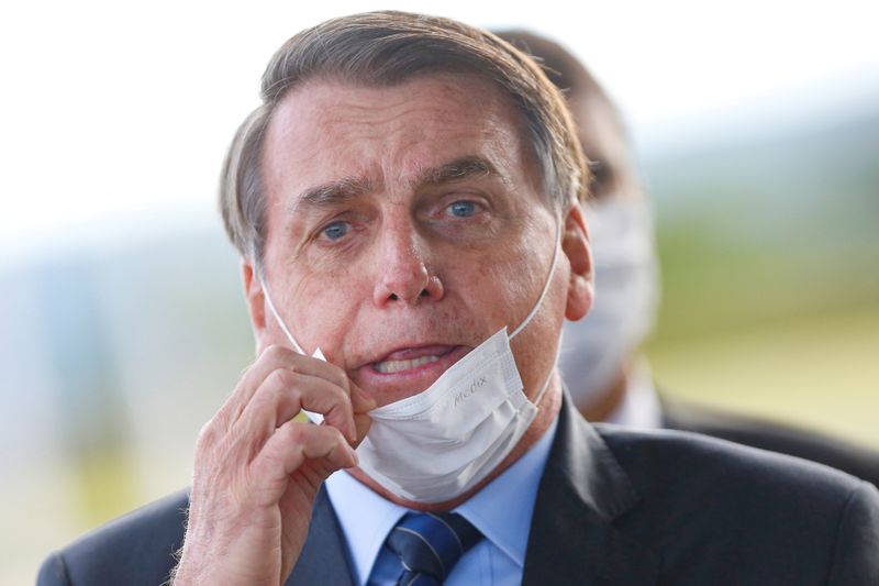 Brazil’s President Jair Bolsonaro adjusts his mask as he leaves