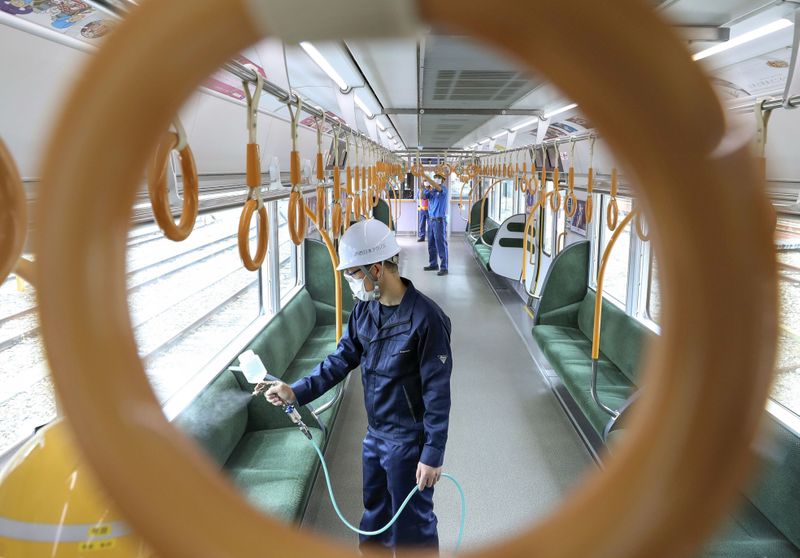 A worker sprays an antiviral liquid inside a train amid