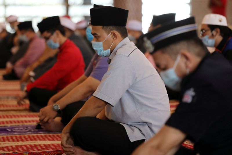 Muslims wearing protective face masks and following social distancing measures