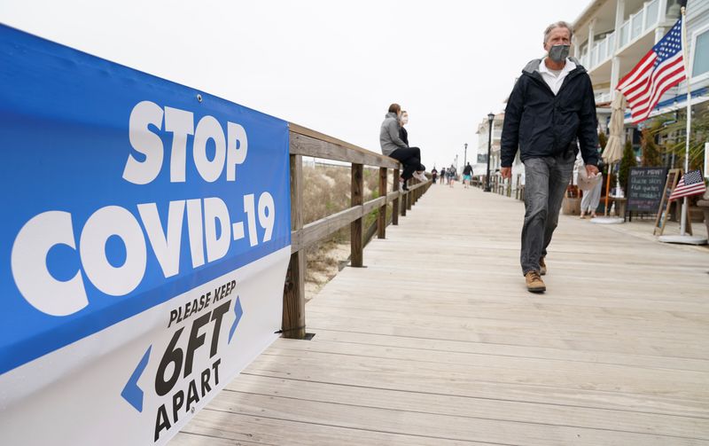 A man passes a COVID-19 sign on the boardwalk at
