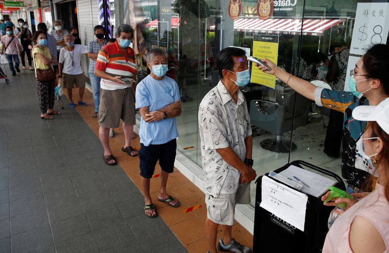Customers queue up to have their temperature taken outside a