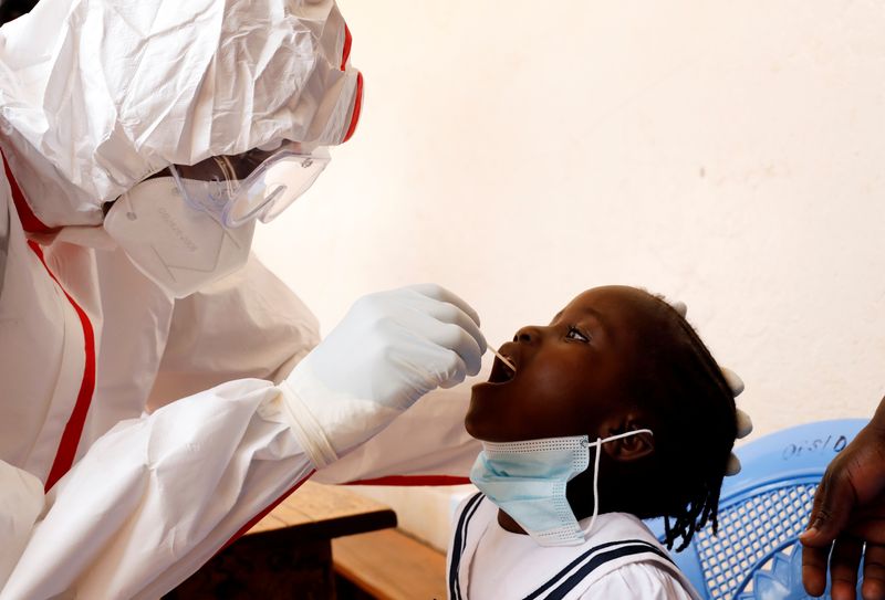 A health worker takes a swab from a child during