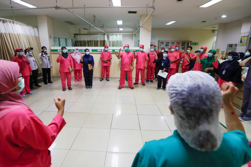 Healthcare workers wearing protective face masks gesture for the coronavirus
