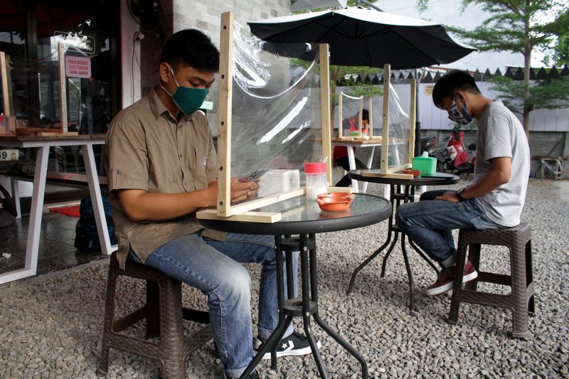 FILE PHOTO: Customers sit with plastic dividers at a cafe