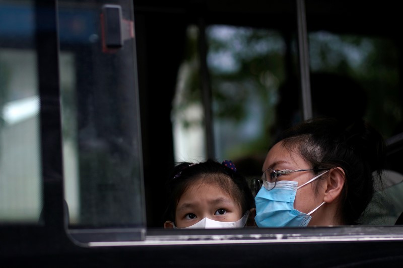 People wearing face masks are seen on a bus following