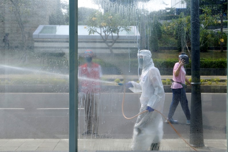 Red cross staff wearing protective suits spray disinfectant to prevent