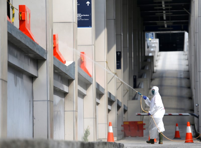 Red cross staff wearing protective suits spray disinfectant to prevent
