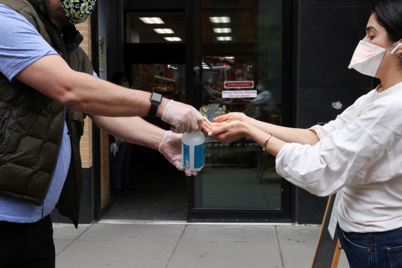 A store worker offers hand sanitizer to shoppers on the