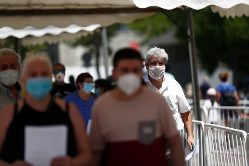 People wearing protective masks queue to be tested at a