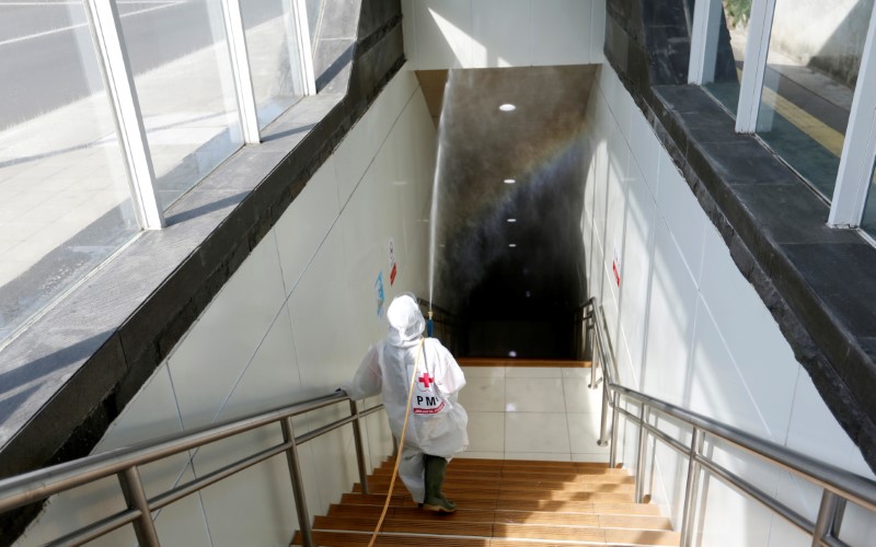 A Red Cross staff member wearing a protective suit sprays