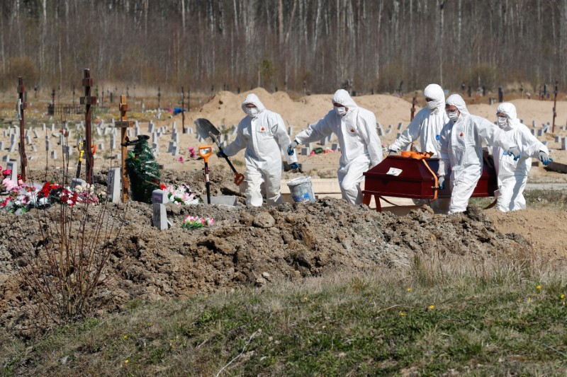 Grave diggers bury a coronavirus disease victim at a graveyard