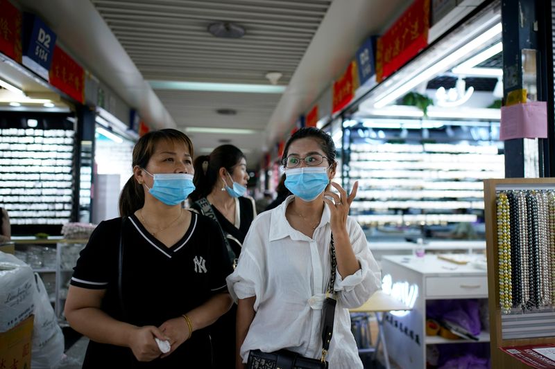 Women wearing face masks talk at the Yiwu Wholesale Market