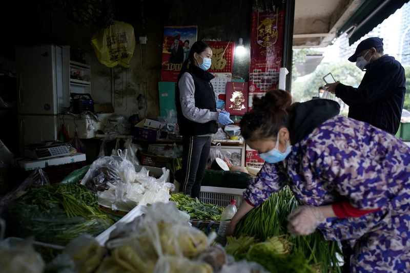 FILE PHOTO: People wearing face masks buy vegetables at a