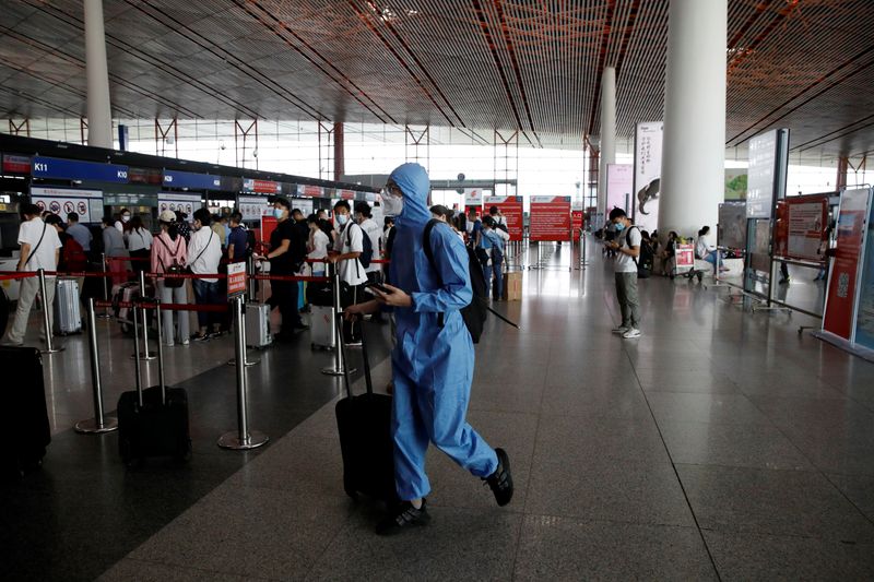 Traveler wearing protective gear walks with luggage at the departure