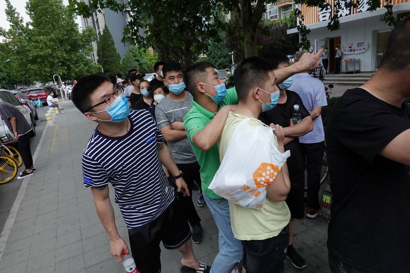 People wearing face masks wait in a line to receive