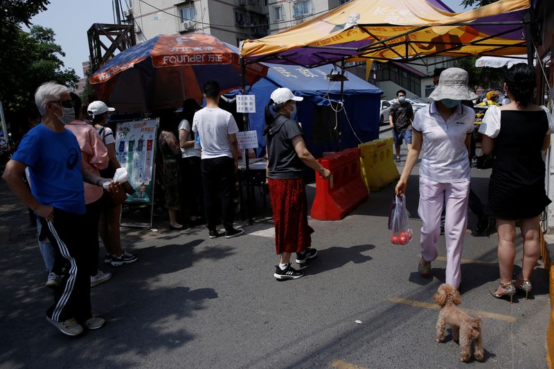 People wearing face mask are seen near tents for registration