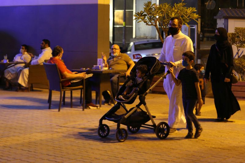 A Saudi family wearing protective face masks walk on Tahlia