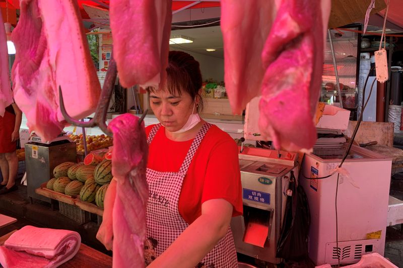 Vendor is seen at a pork stall at a market